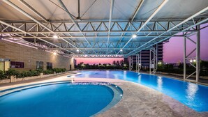 A swimming pool with a covered area, surrounded by a low wall and some greenery. - Crowne Plaza Foshan by IHG (Foshan)