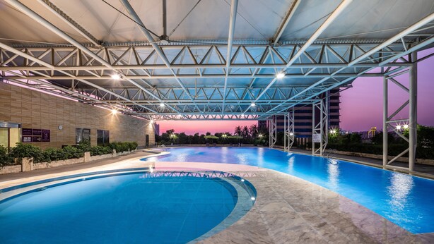 A swimming pool with a covered area, surrounded by a low wall and some greenery. - Crowne Plaza Foshan by IHG (Foshan)