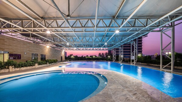 A swimming pool with a covered area, surrounded by a low wall and some greenery. - Crowne Plaza Foshan by IHG (Foshan)