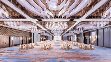 Un lobby moderno y espacioso de hotel, con un área de estar central, techos altos y una lámpara decorativa.