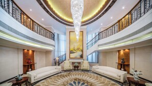 A spacious lobby with a large chandelier, two sofas, a fireplace, and a large painting on the wall. - Crowne Plaza Foshan by IHG (Foshan)