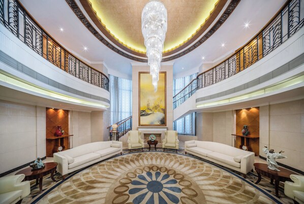 A spacious lobby with a large chandelier, two sofas, a fireplace, and a large painting on the wall. - Crowne Plaza Foshan by IHG (Foshan)