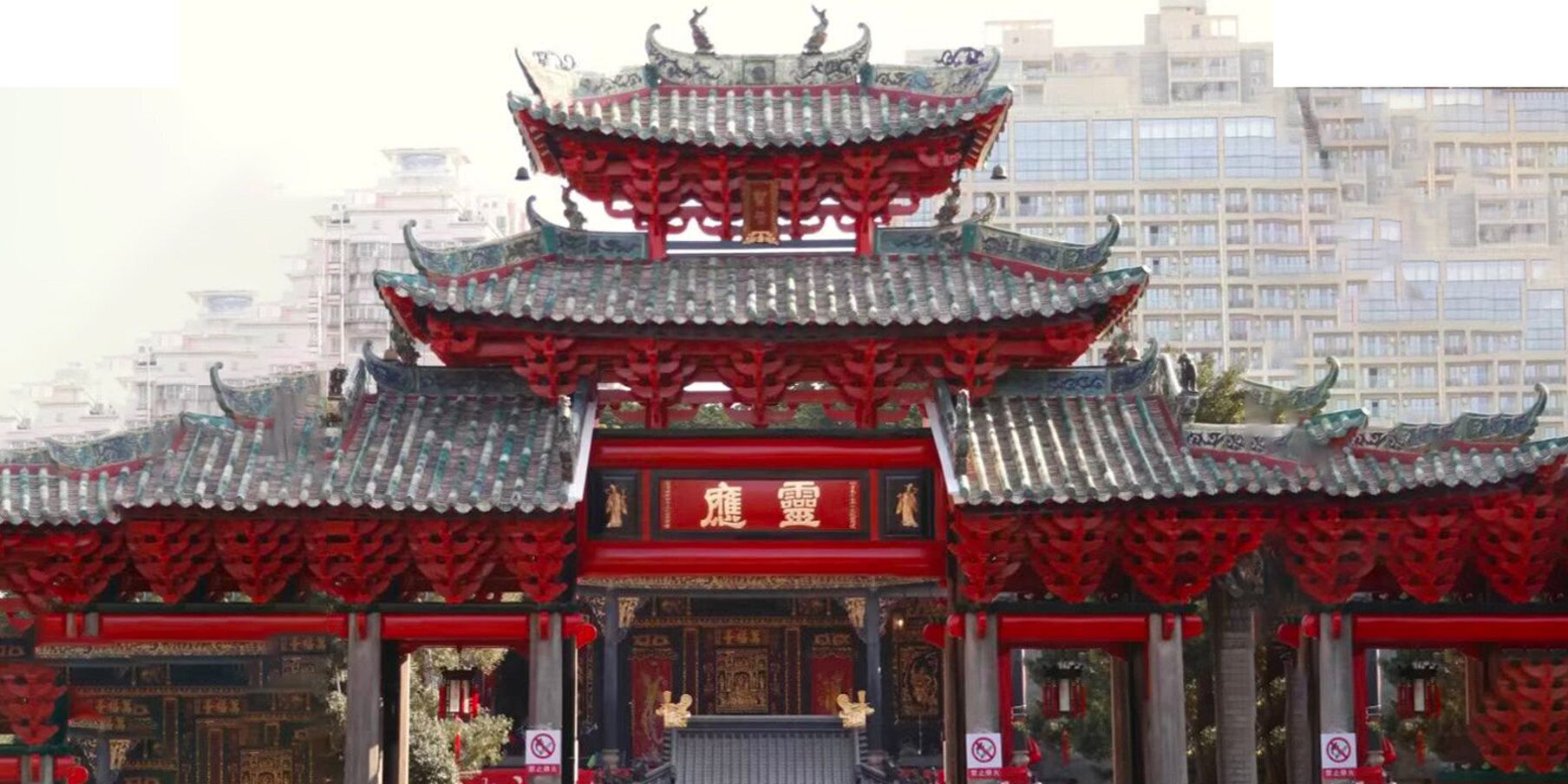 Una puerta tradicional china con diseños intrincados en el techo y detalles en rojo.