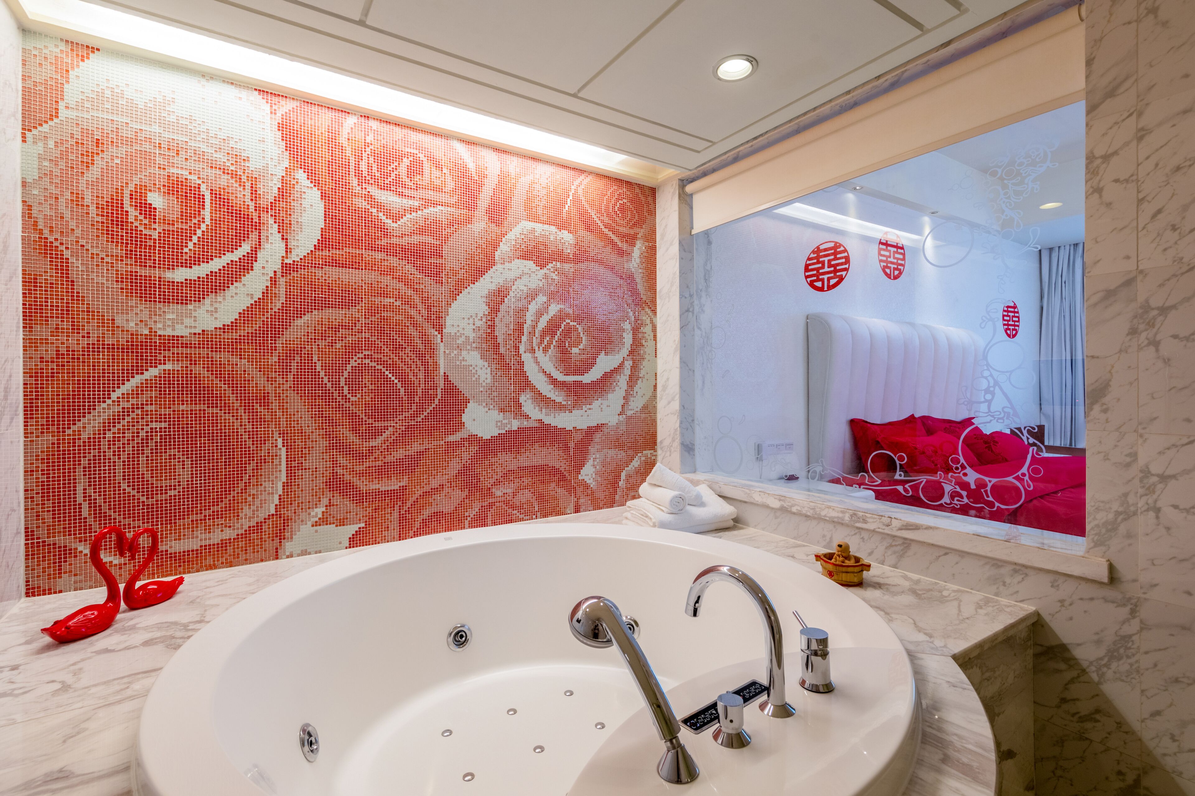 A modern bathroom with a large bathtub, a mirror, and a decorative wall with a floral pattern.