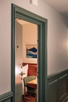 Una habitación de hotel con un escritorio de madera, una silla verde y un cuadro en la pared.
