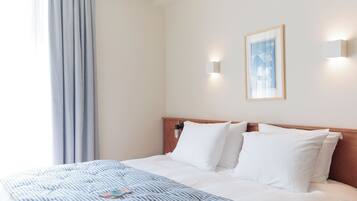 A hotel room with a bed, a bedside table, a lamp, and a framed picture on the wall.