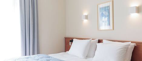 Habitación de hotel con una cama, una mesita de noche, una lámpara y un cuadro en la pared.