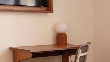 Une chambre à coucher avec un bureau en bois, une chaise, une table de chevet et un lit.