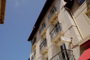 Un edificio de varios pisos con balcones y un cartel que indica 'Alfred Hotels' con un precio.