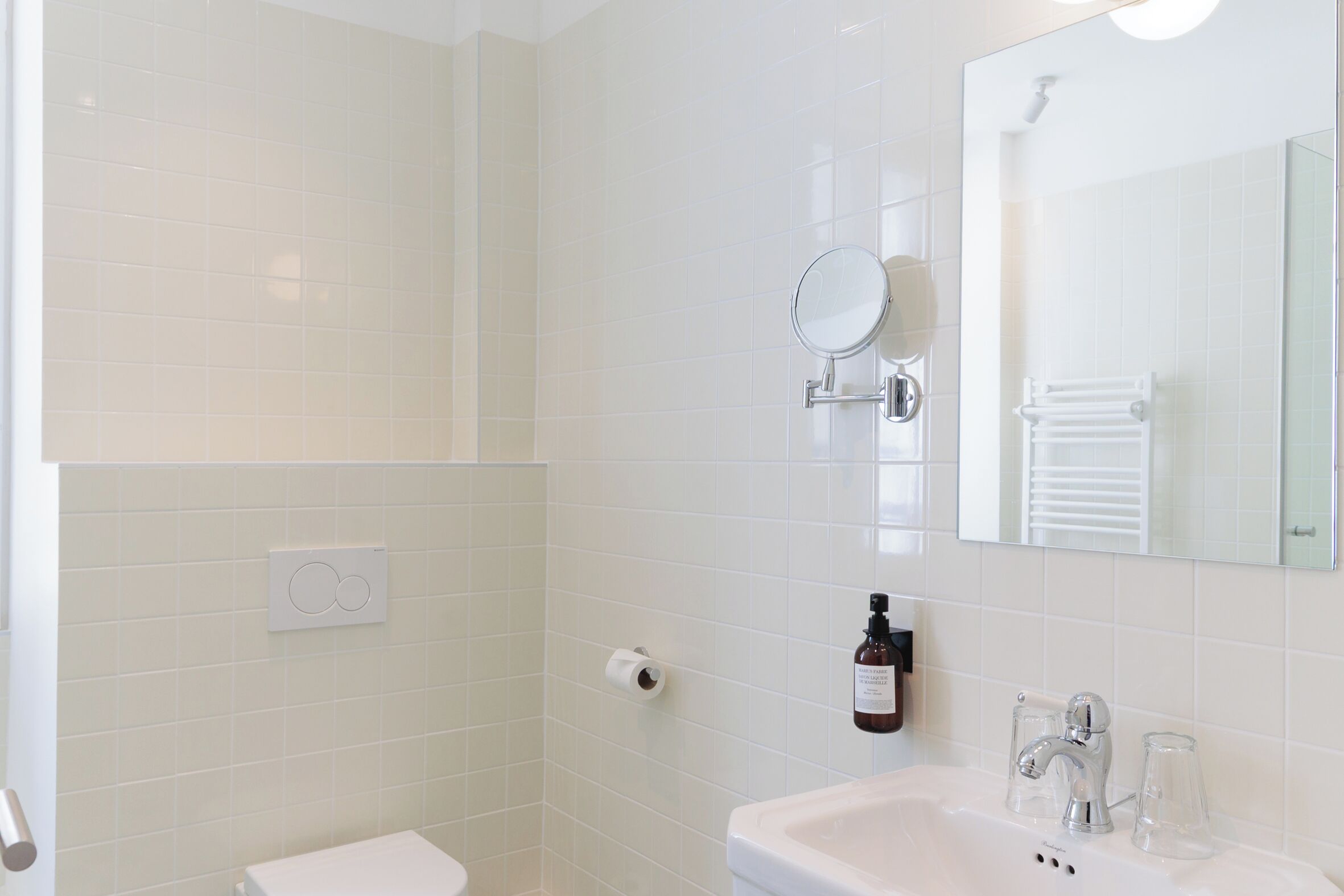 A bathroom with a toilet, sink, mirror, and towel rack.
