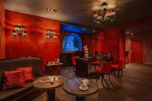 A modern lounge with a red color scheme, a sofa, a coffee table, and a bar area.