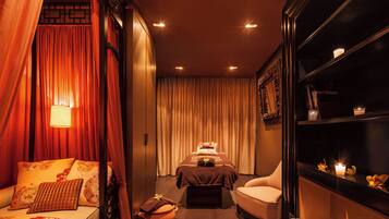 Una habitación con una cama, una silla, una mesita y un estante con velas.