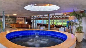 A modern indoor pool area with a central fountain, surrounded by seating and a reception desk. - Club Mahindra Puducherry (Bahur)