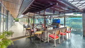 A covered outdoor bar area with seating, a stone counter, and a view of greenery. - Club Mahindra Puducherry (Bahur)