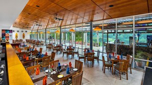 A spacious restaurant with wooden ceiling and large windows offering a view of the outdoors. - Club Mahindra Puducherry (Bahur)
