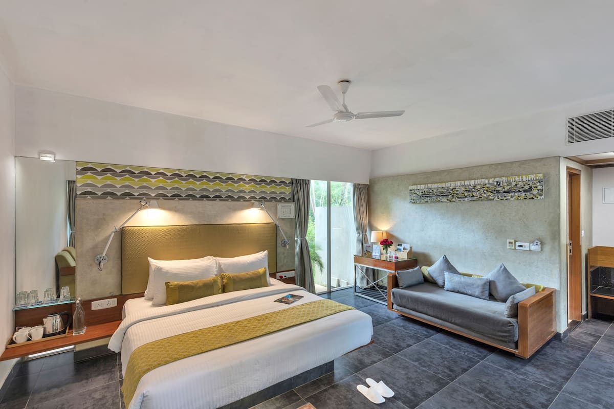 A hotel room with a bed, a sofa, a desk, and a large window.