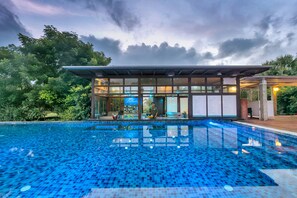 A swimming pool with a tiled deck, a covered seating area, and a bar. - Club Mahindra Puducherry (Bahur)