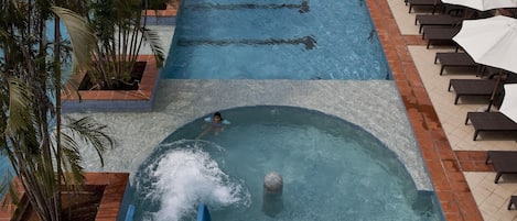 A swimming pool with a water slide, lounge chairs, and a covered seating area.