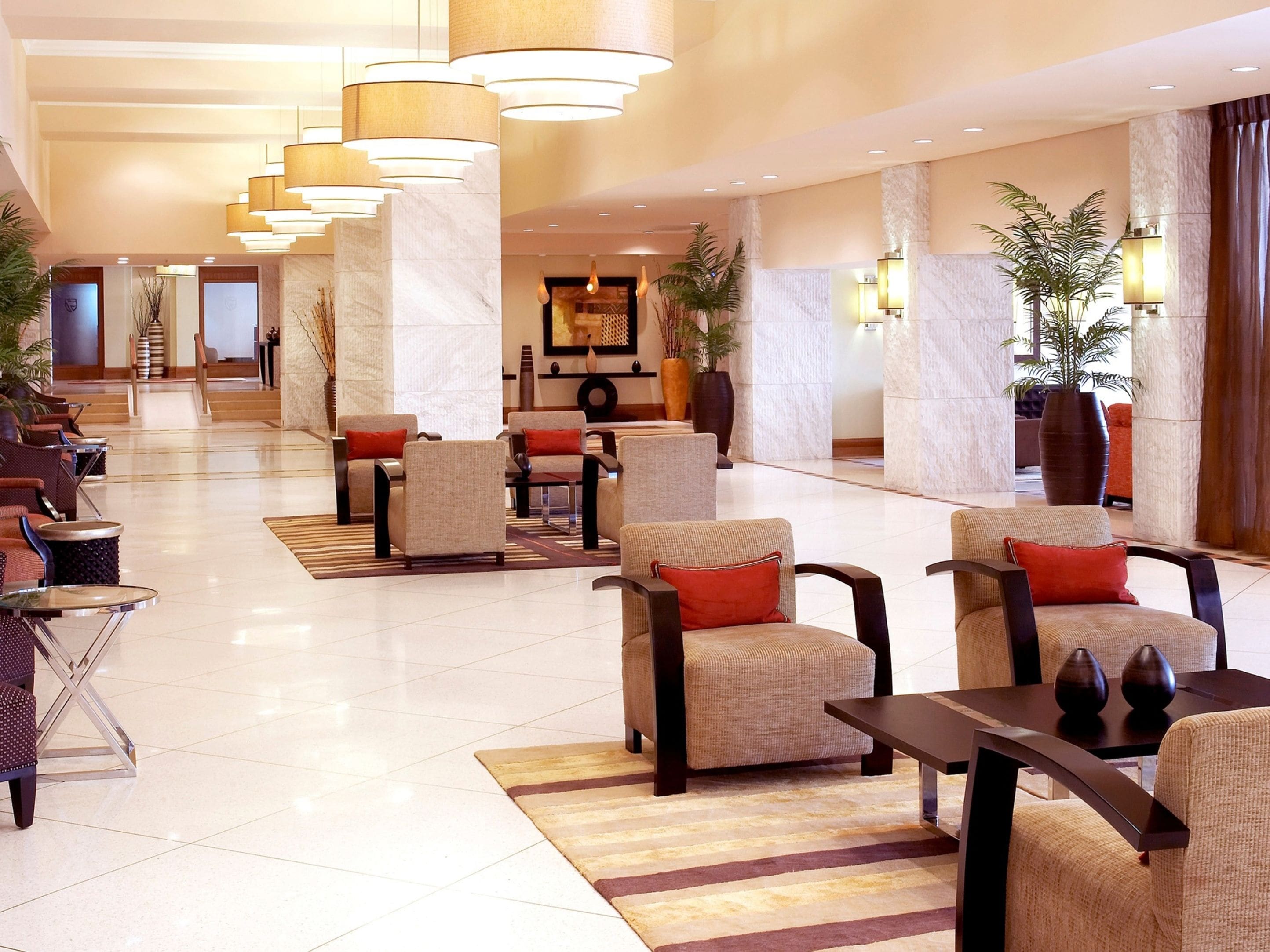 A spacious lobby with multiple seating areas, including sofas and armchairs, and a central reception desk.