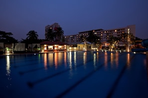 Relax by the pool surrounded by palm trees in a tranquil resort setting.