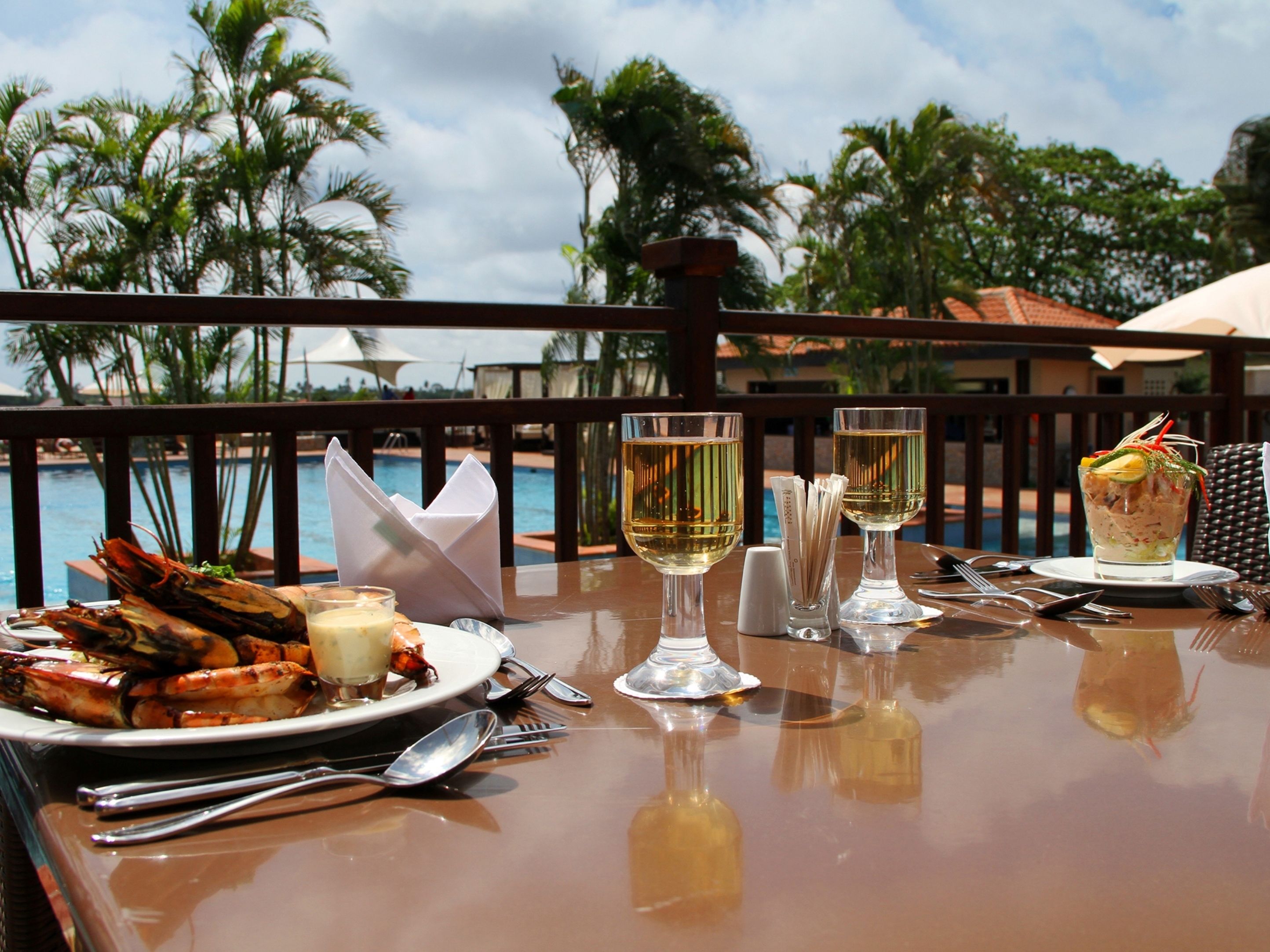 A dining table with seafood, wine glasses, and a tropical view.