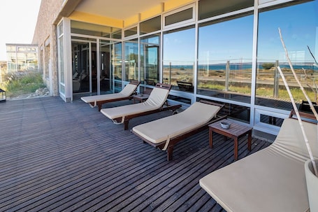 A deck with wooden loungers and a glass wall offering a view of the landscape.