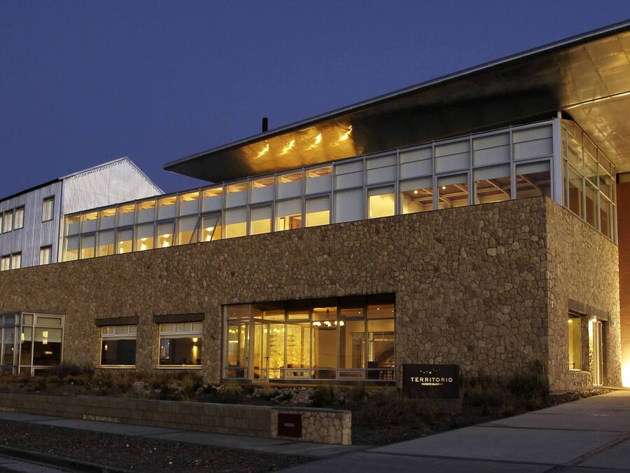 A modern building with a stone facade, large windows, and a flat roof.