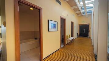 Un corridoio d'hotel con pavimento in legno, una panca e un quadro appeso al muro.