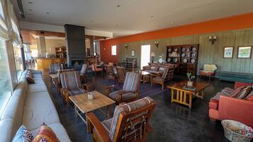 Un hall amplio con un sofá grande, varias sillas, una mesa de centro y una chimenea.