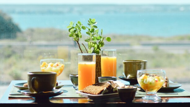 Una mesa de desayuno con diversos platos y bebidas, con vistas a un paisaje pintoresco.
