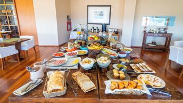 Un bufé de desayuno con diversas opciones de comida y cubiertos sobre una mesa de madera.