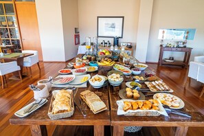 A breakfast buffet with various food items and utensils on a wooden table. - Hotel Territorio (Puerto Madryn)