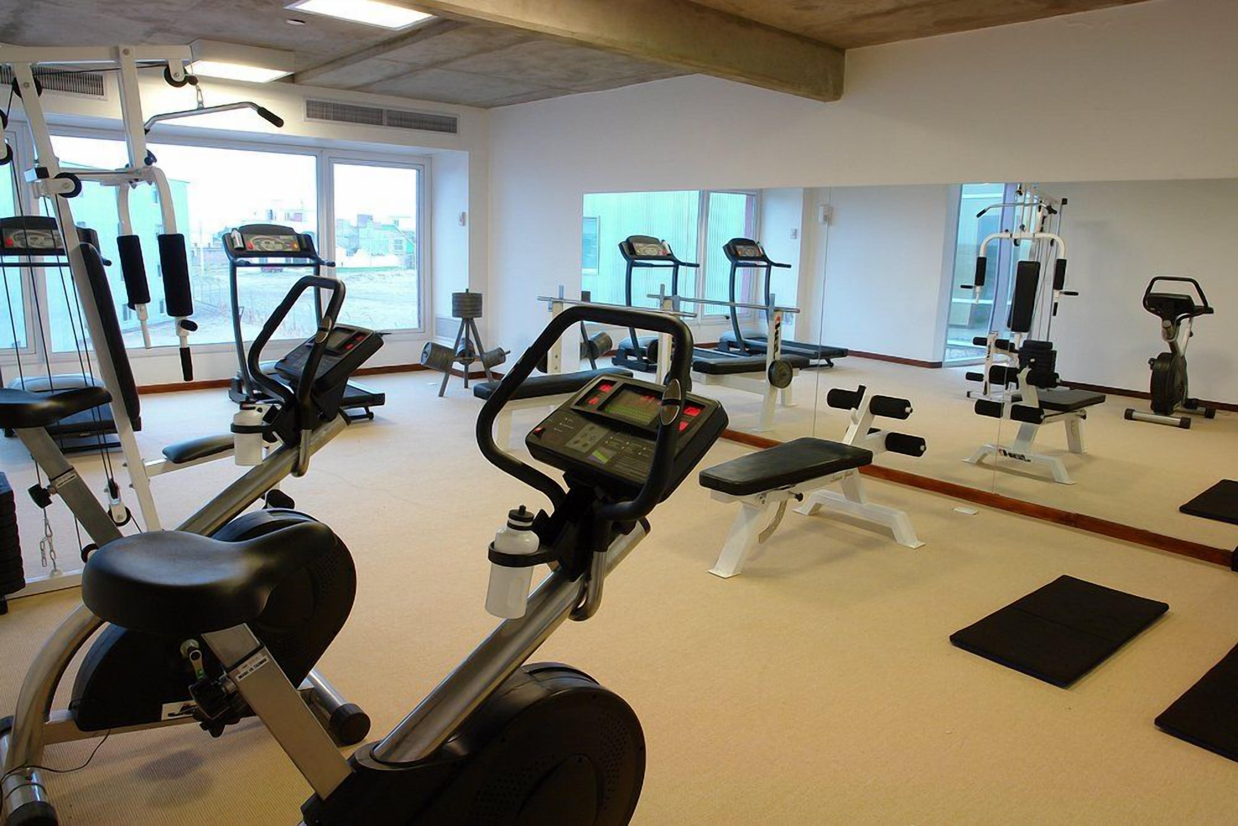 A gym with cardio machines, weight stations, and benches.
