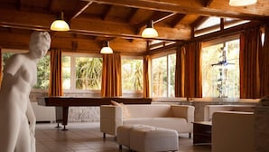 A spacious room with a pool table, a white sofa, and a statue. - Saron Hotel (Lavreotiki)