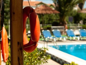 A poolside area with lounge chairs and a lifebuoy hanging on a pole.
