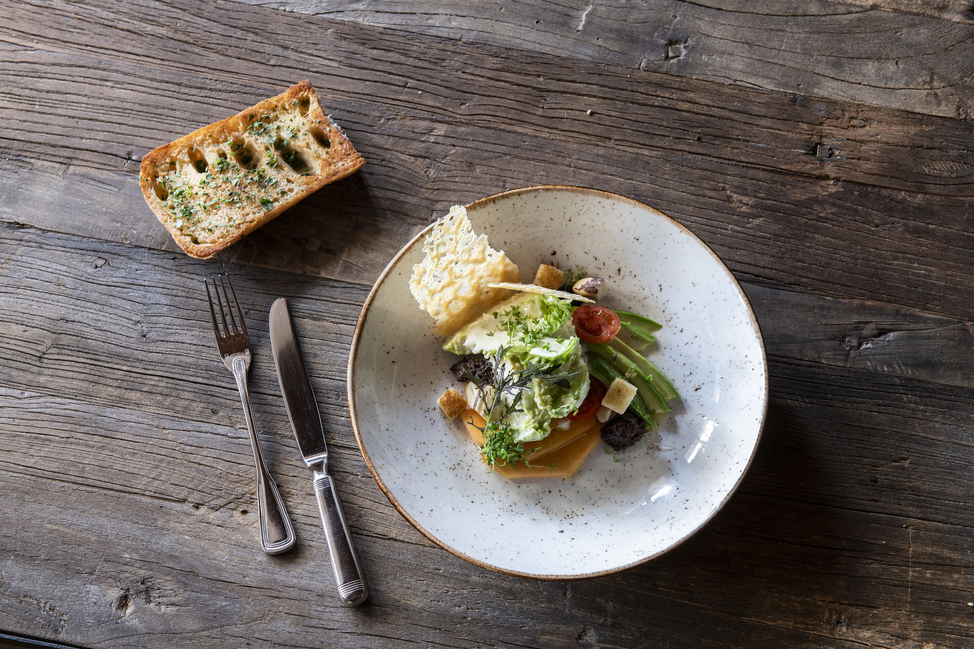 A plate of food with a fork and knife on a wooden table.