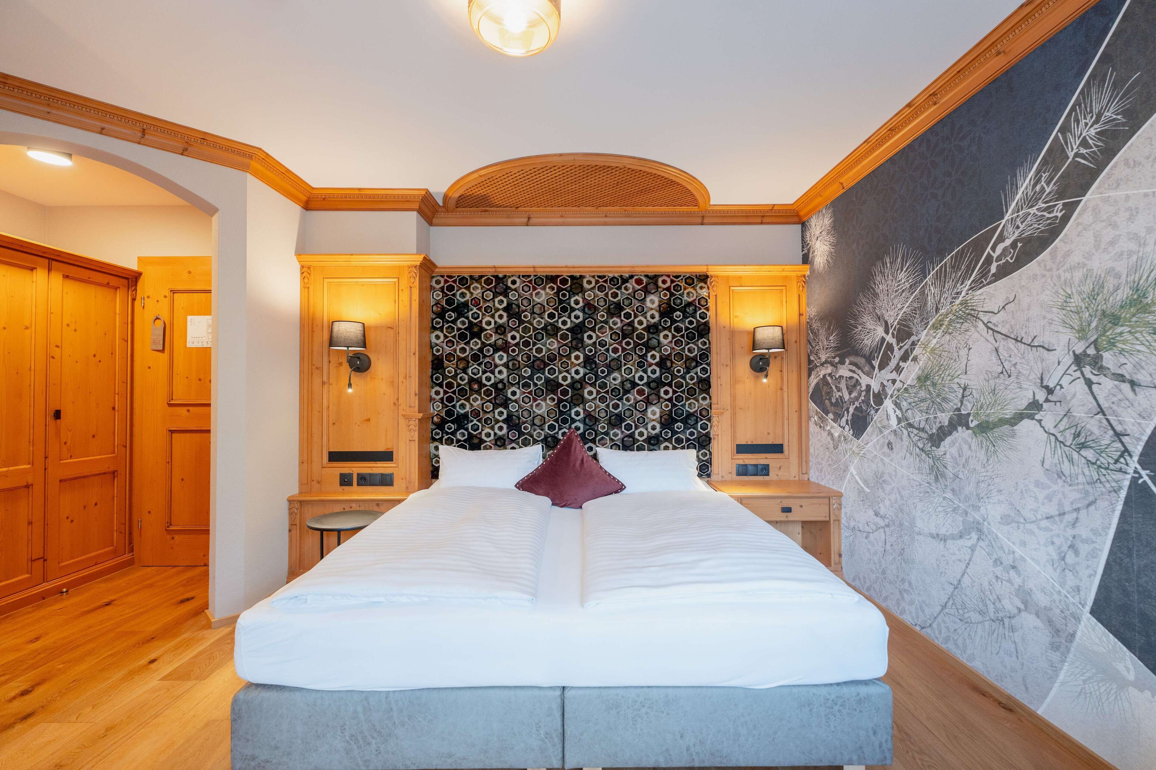 Quarto bem arrumado com uma cama grande, cabeceira de madeira e um mural na parede.
