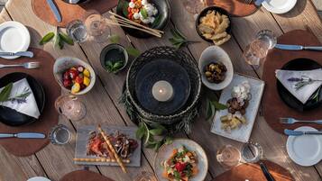 A round wooden table set for a meal with plates, cutlery, and various dishes.