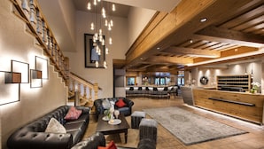 A spacious living area with leather sofas, a wooden staircase, and a dining area with modern chairs and a wooden bar. - das Alois (Tux)