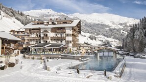 A snow-covered mountain resort with a large building featuring balconies and a pool area. - das Alois (Tux)