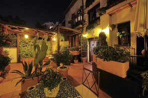 A courtyard with potted plants, a pergola, and a wooden table.