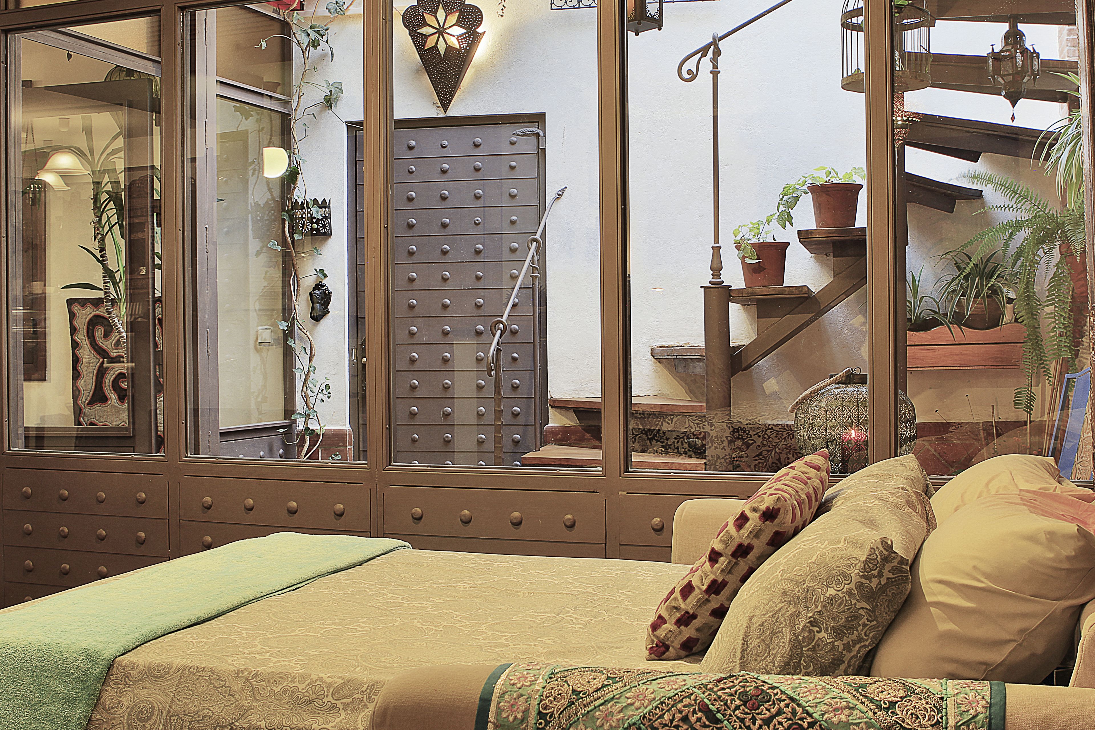 Quarto com cama, penteadeira e janela com vista para uma escadaria e plantas em vasos.