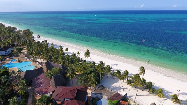 Un resort en la playa con piscina, palmeras y vistas al océano.