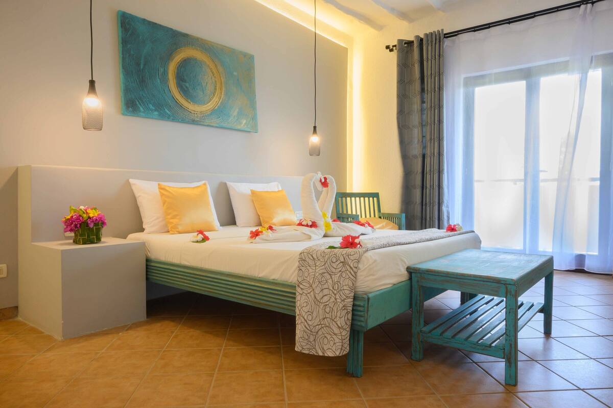 A well-lit bedroom with a bed, bedside table, and a small table.