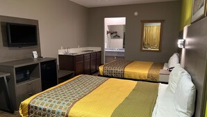 Une chambre d’hôtel avec deux lits, un bureau, une télévision, un miroir et une kitchenette.