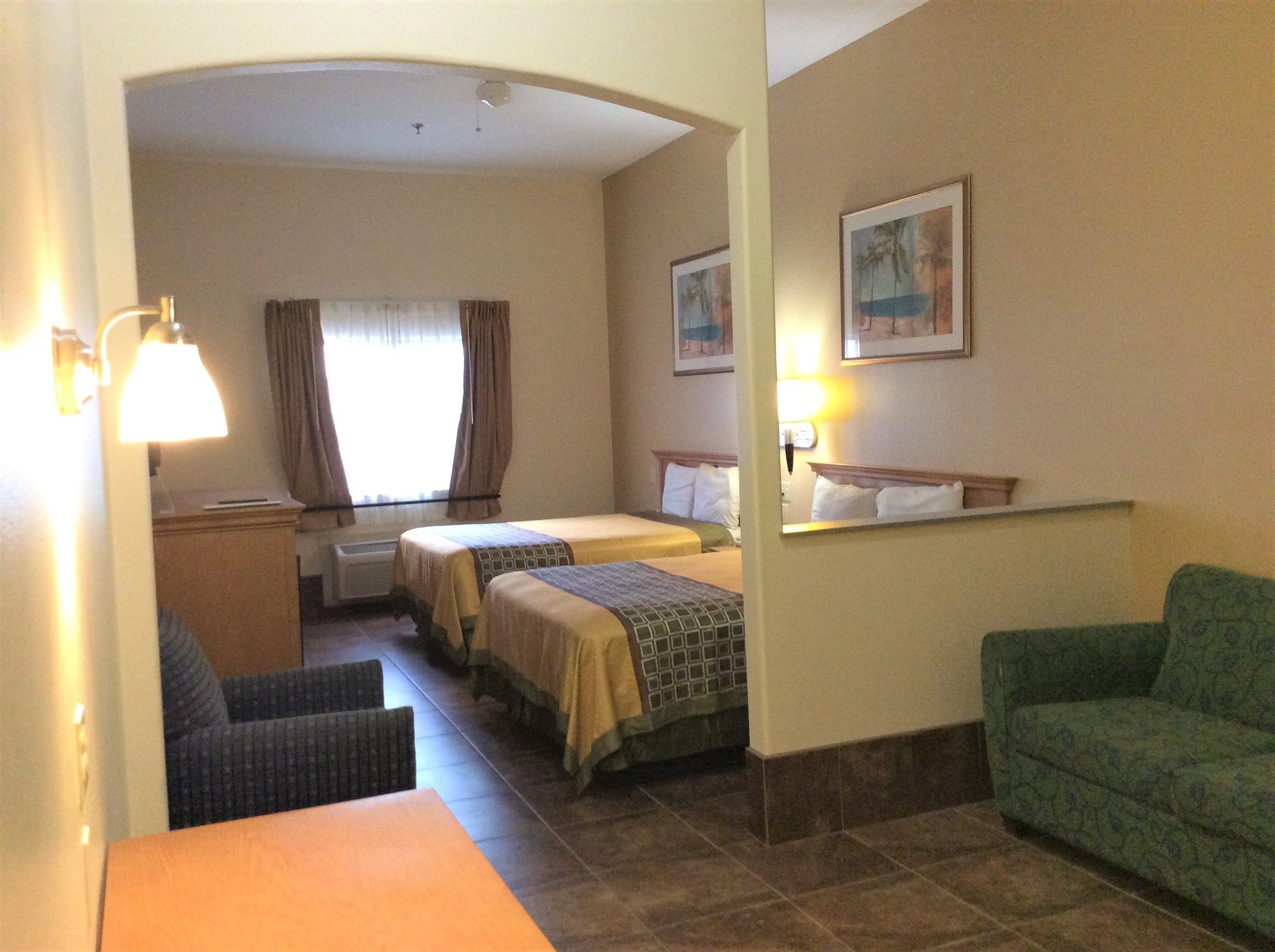 A hotel room with two beds, a desk, a chair, and a couch.