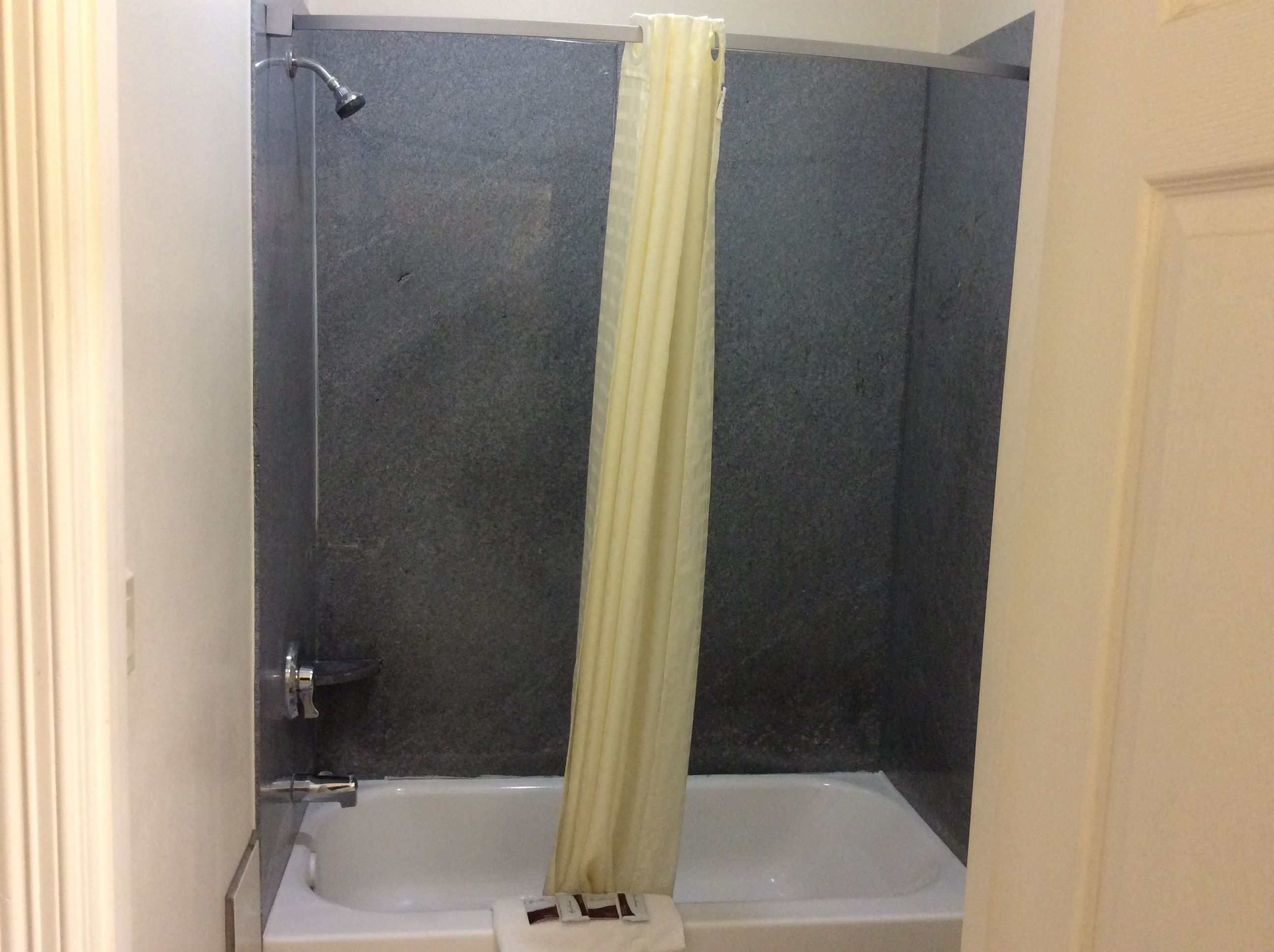 A bathroom with a shower and bathtub, a towel rack, and a door.