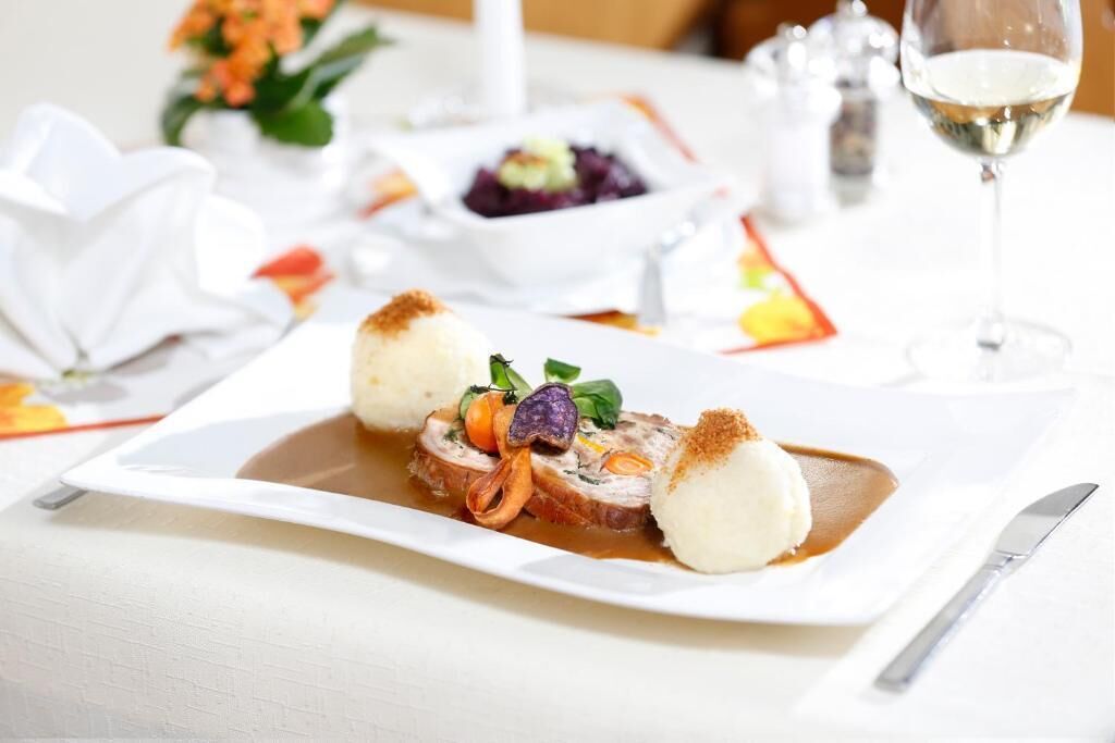 A plated dish with a sauce, a white spherical item, and a garnish.