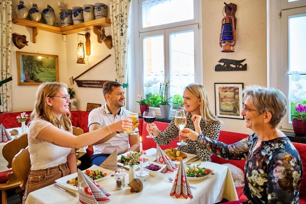 A group of people dining at a restaurant with a table set for a meal, surrounded by various decorative items and a window with a view.