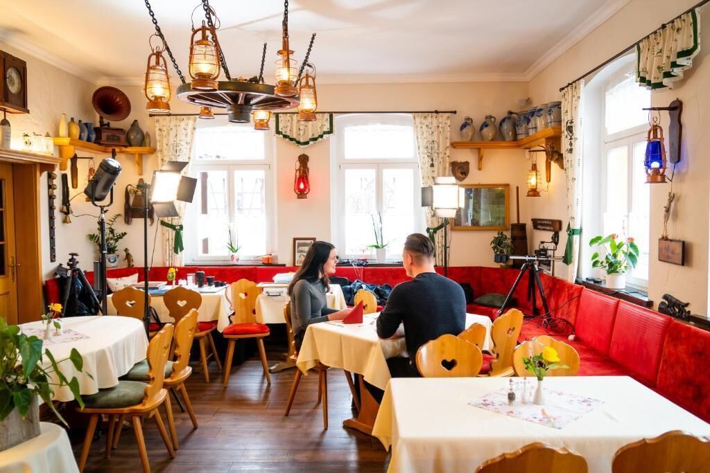 Un restaurante acogedor con sillas y mesas de madera, y un sofá rojo.